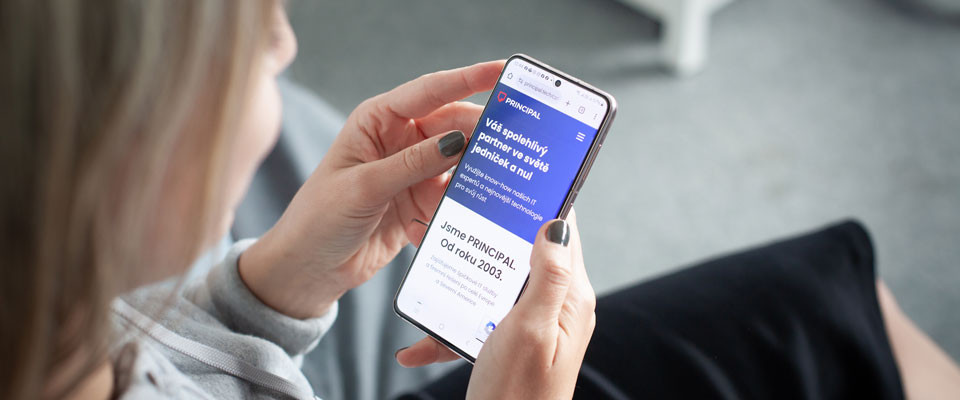 Žena drží chytrý telefon a prohlíží si webové stránky společnosti PRINCIPAL na displeji mobilního telefonu.